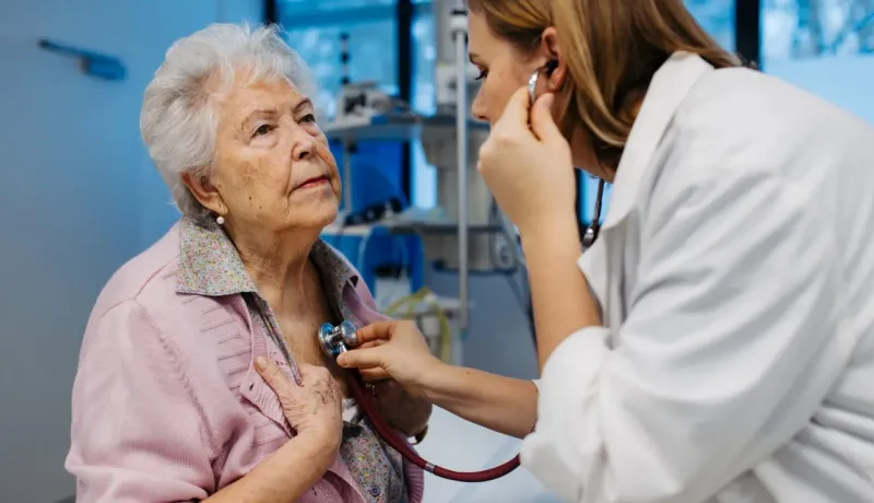 Une femme médecin examine une patiente âgée avec un stéthoscope.