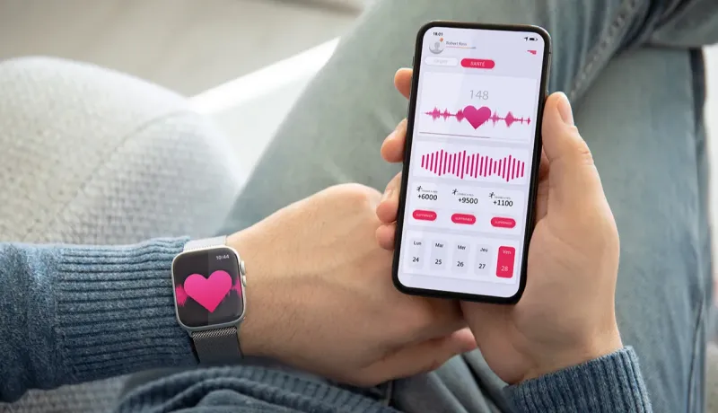 Un homme regarde les données de son cœur sur une application mobile et sa montre connectée.