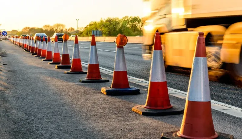 Une rangée de cônes de signalisation orange et blancs délimite une zone sur le bord d'une route.