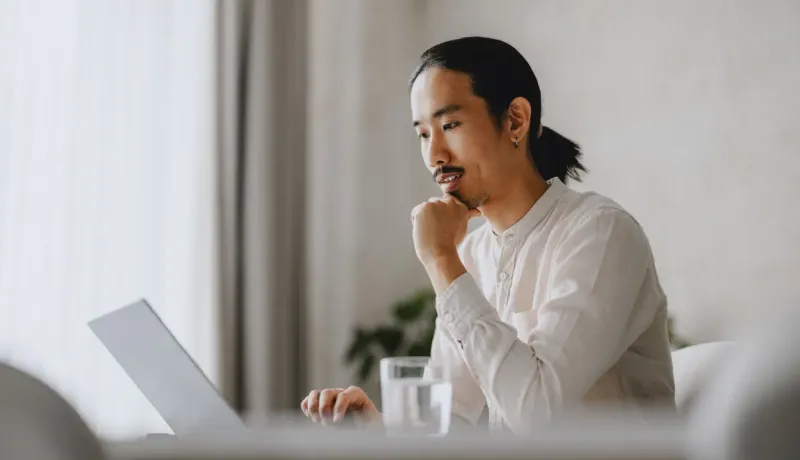 Un homme assis sur un canapé, concentré sur son ordinateur portable.