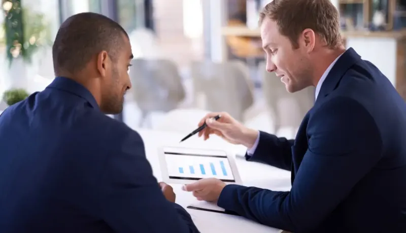 Deux hommes d'affaires sont en pleine discussion formelle devant une tablette.