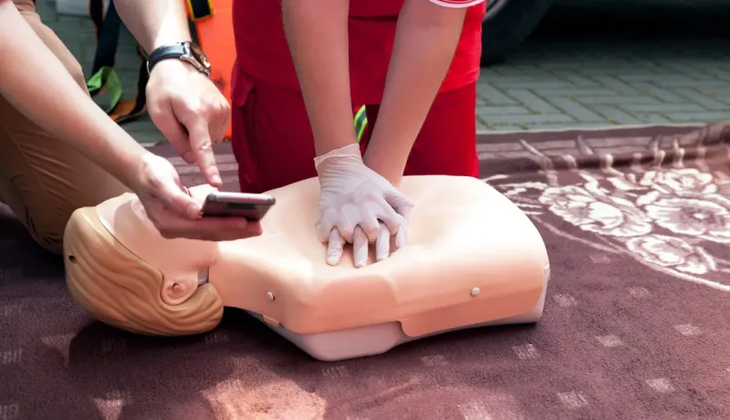 Deux personnes pratiquent la réanimation cardio-pulmonaire sur un mannequin.