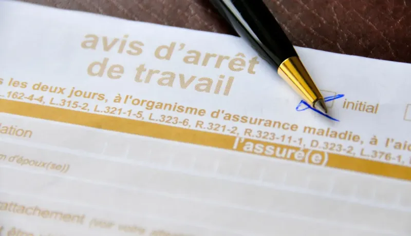 Gros plan d'un formulaire d'avis d'arrêt de travail avec un stylo.