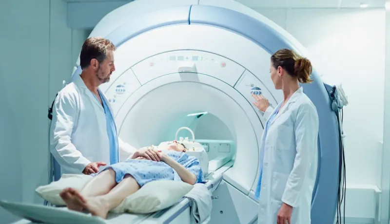 Des médecins préparent un patient pour une IRM, surveillant les réglages de l'appareil.