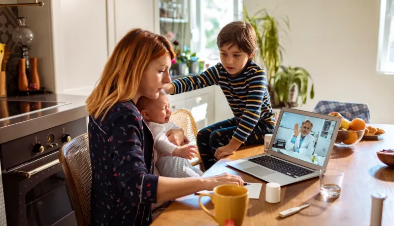 Une mère avec son bébé et son fils assistent à une téléconsultation médicale sur ordinateur.