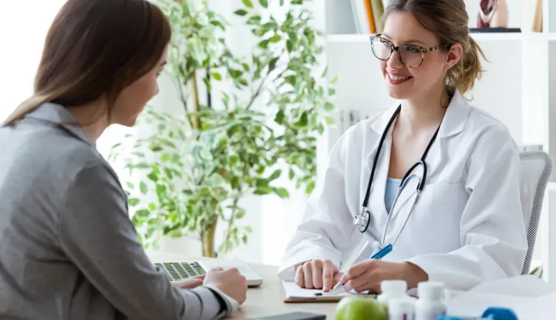 Une femme médecin souriante et une patiente discutent lors d'une consultation au cabinet.