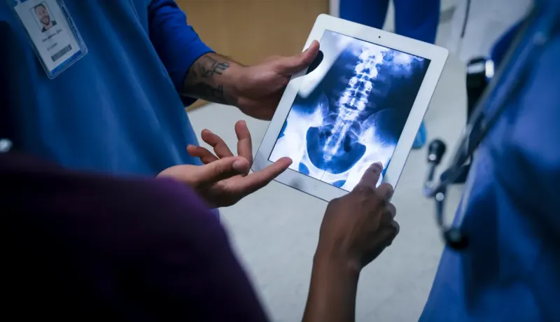 Un médecin tenant une tablette affichant une image radiographique.