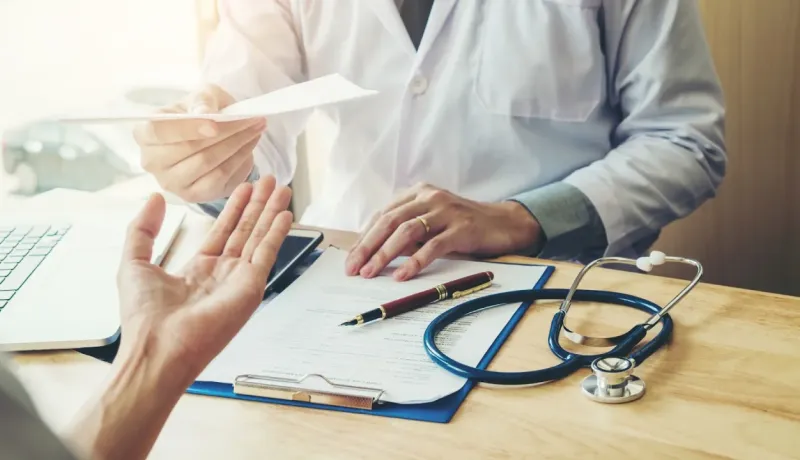 Un médecin remet une ordonnance ou des documents à un patient lors d'une consultation.