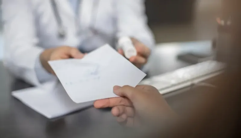 Un médecin remet une ordonnance ou des documents médicaux à un patient assis.