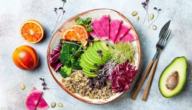 Un bol coloré rempli d'une salade végétalienne avec avocat, quinoa et légumes frais, prêt à être dégusté.