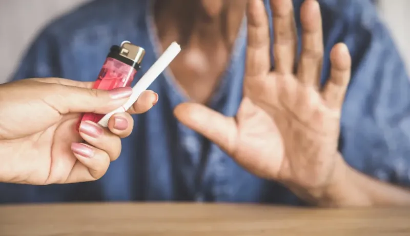 Une personne refuse une cigarette tendue par une autre main, faisant un signe d'arrêt.