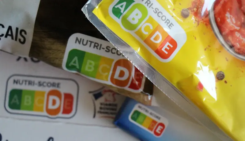 Gros plan sur plusieurs emballages de produits alimentaires affichant clairement le logo Nutri-Score avec différentes évaluations.