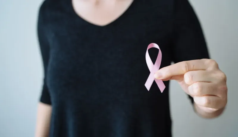 Main tenant un ruban rose, symbole de la lutte contre le cancer du sein.