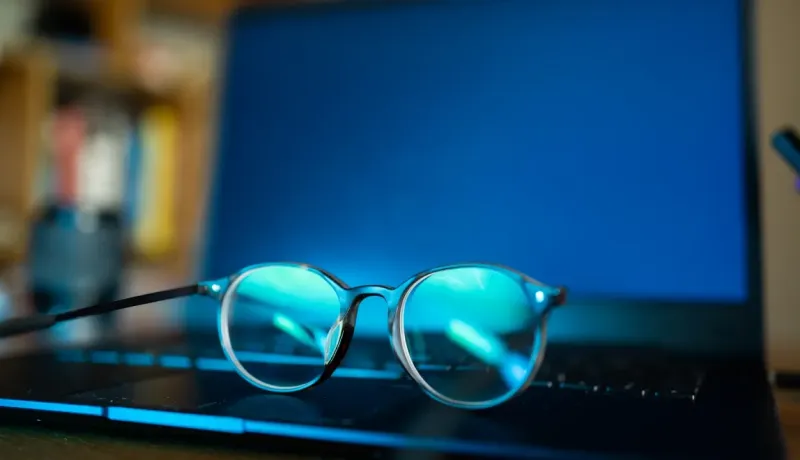 Lunettes anti-lumière bleue posées sur un ordinateur portable allumé.