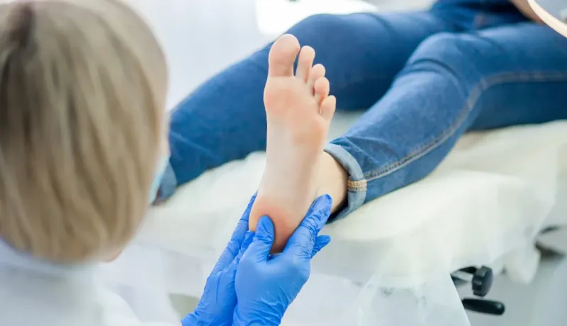 Podologue examinant le pied d'un patient, soin des membres inférieurs.