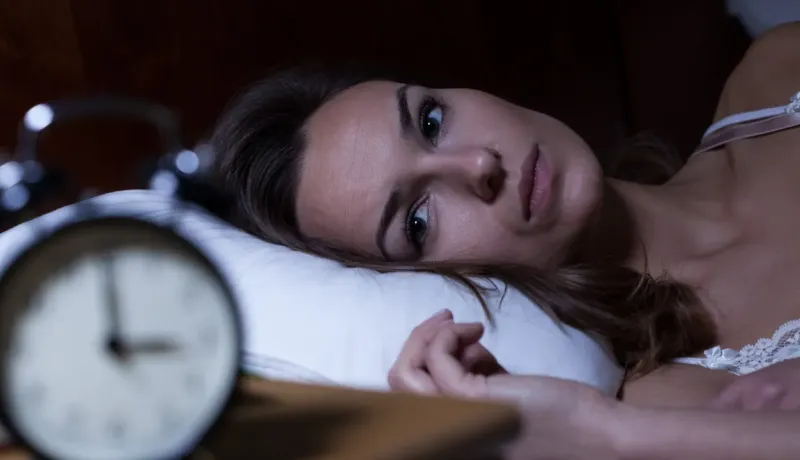 Femme allongée, fixant l'alarme, souffrant d'insomnie.