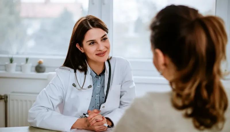 Médecin souriante discutant avec une patiente lors d'une consultation.