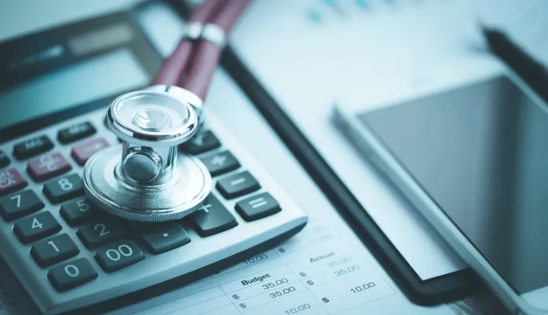 Stéthoscope et calculatrice sur des documents financiers, coût de la santé.