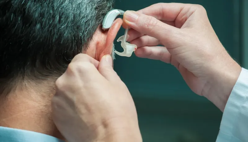 Pose d'un appareil auditif dans l'oreille d'une personne.