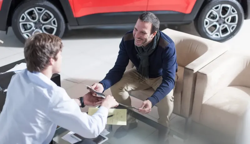 Un commercial d'une consession automobile et un acheteur sont assis et discutent