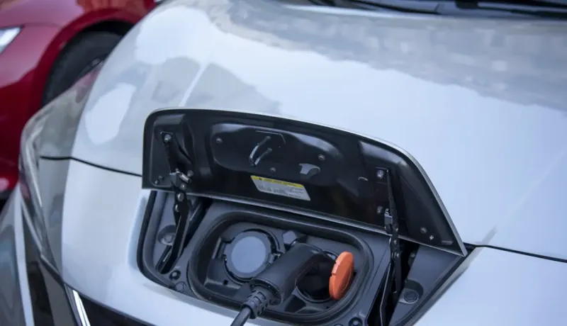 Gros plan sur le port de charge d'une voiture électrique grise avec le câble branché.