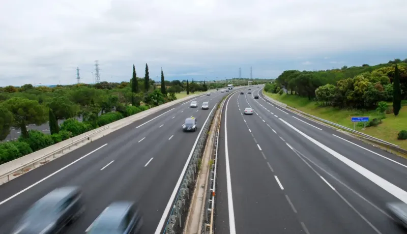 Vue aérienne d'une autoroute à plusieurs voies avec du trafic et des arbres le long des côtés.