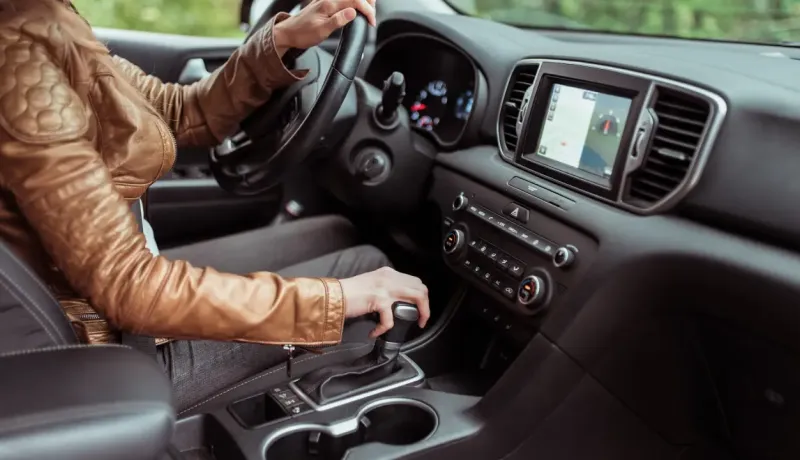 Gros plan d'une personne conduisant un SUV, les mains sur le volant et le levier de vitesses.