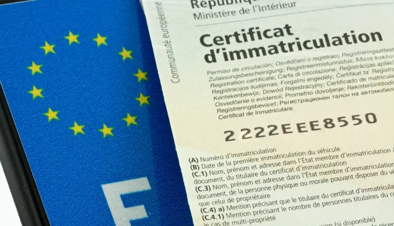 Gros plan sur un certificat d'immatriculation européen français et une plaque d'immatriculation française.