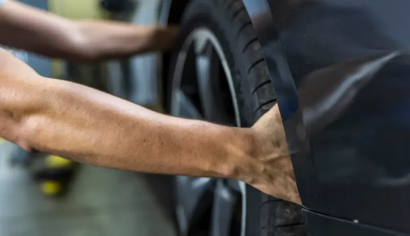 Gros plan sur les mains d'un homme installant un pneu de voiture.