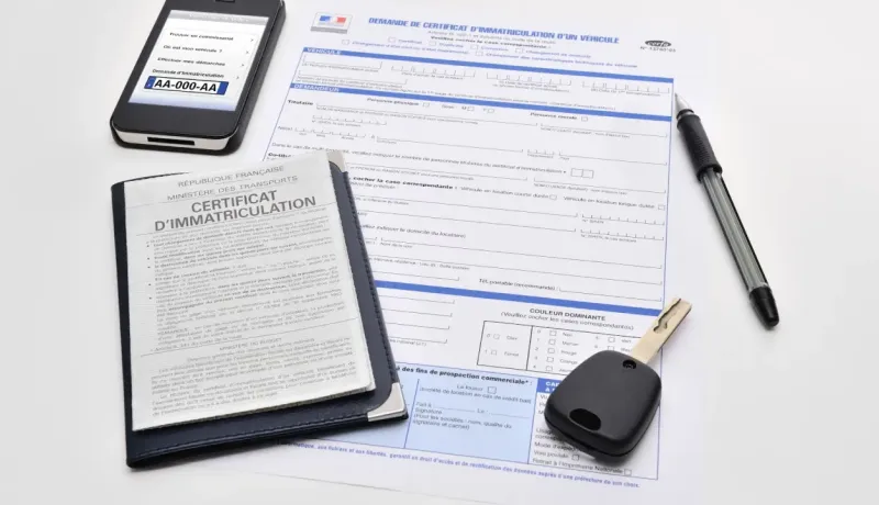 Un téléphone, une clé de voiture et un stylo posés sur un formulaire de demande de certificat d'immatriculation français.