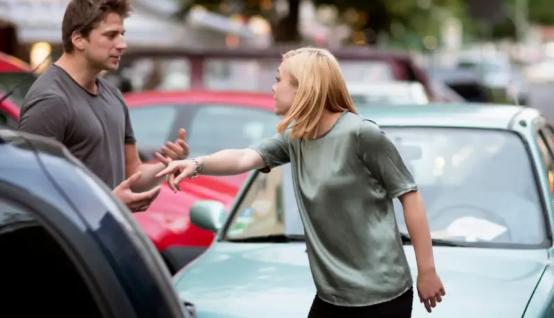 Un homme et une femme se disputent à propos d'une voiture, montrant des expressions de frustration et de désaccord.