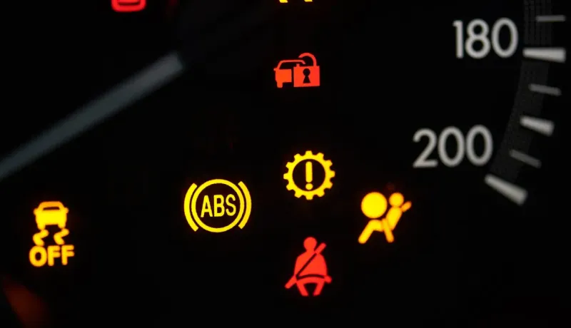 Gros plan sur le tableau de bord d'une voiture avec plusieurs voyants d'alerte allumés.