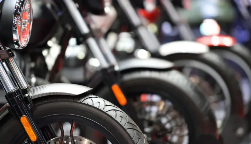 Un gros plan sur les roues avant et les phares de plusieurs motos alignées, mettant en valeur leur design.