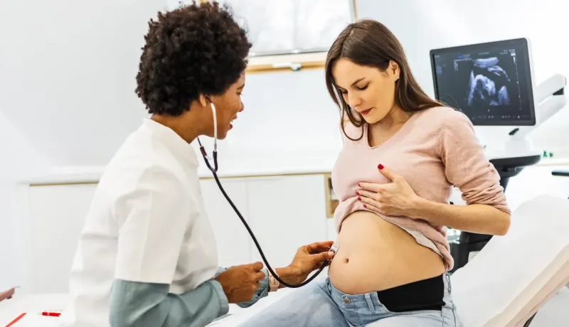 Un professionnel de santé écoute le ventre d'une femme enceinte.