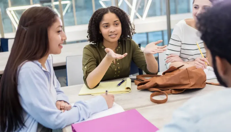 Des étudiants collaborent et discutent autour d'une table de travail.