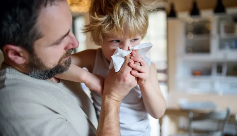Père aidant son jeune fils à se moucher.