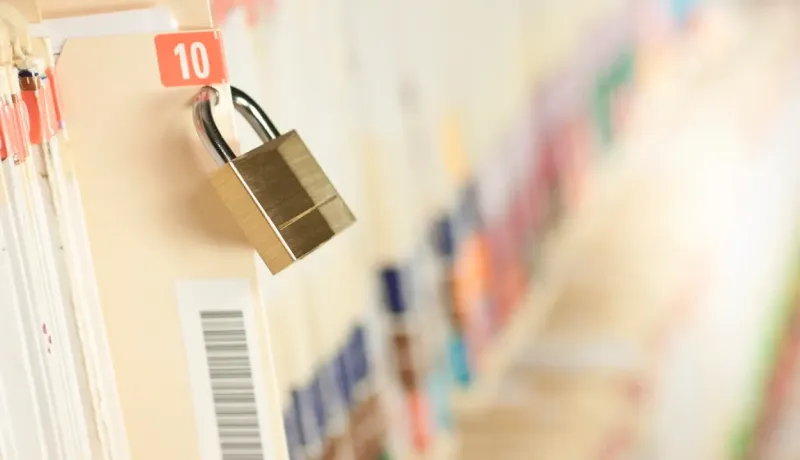 Un cadenas doré verrouille un dossier numéroté 10, symbolisant la sécurité des données, sur une étagère remplie de fichiers colorés.