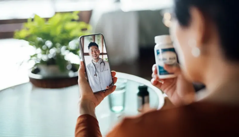 Une personne montre des médicaments à un médecin sur smartphone.