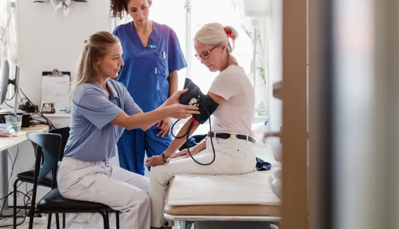 Une infirmière mesure la pression artérielle d'une patiente âgée.