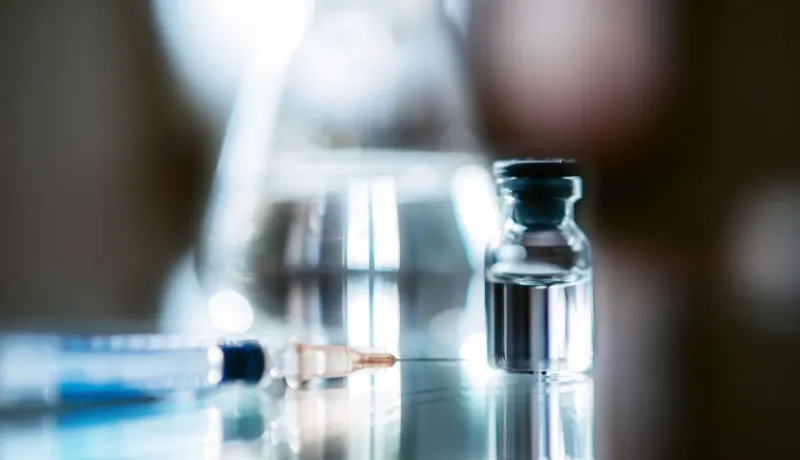Une seringue et un flacon en verre, prêts pour une injection.