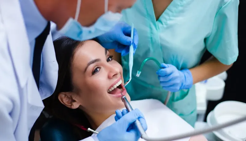 Un dentiste et son assistant soignent une patiente dans un cabinet.