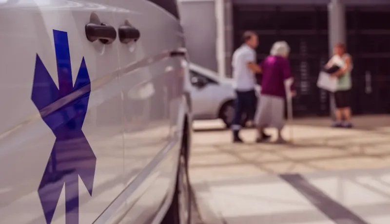 Gros plan sur le logo d'une ambulance, avec des personnes floues derrière.