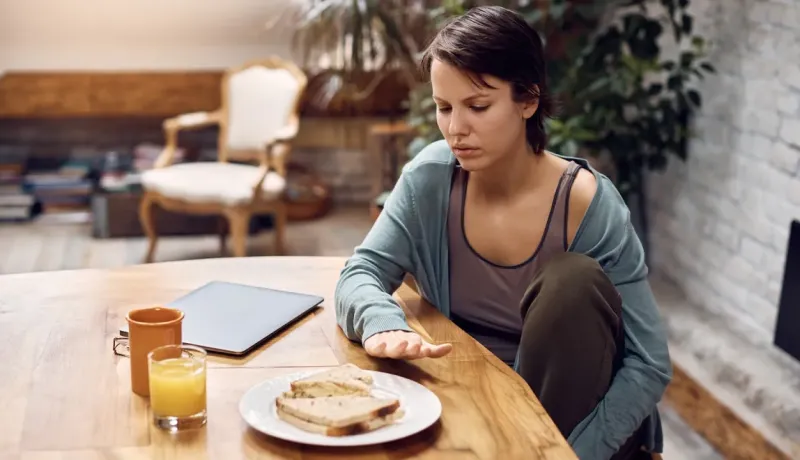 Une femme face à son repas semble ne pas vouloir manger.