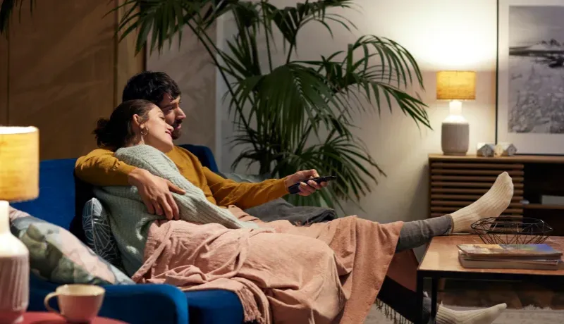 Un homme et une femme assis sur un canapé devant une télévision.