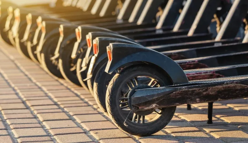 Des trottinettes électriques en ligne sur un trottoir en briques.
