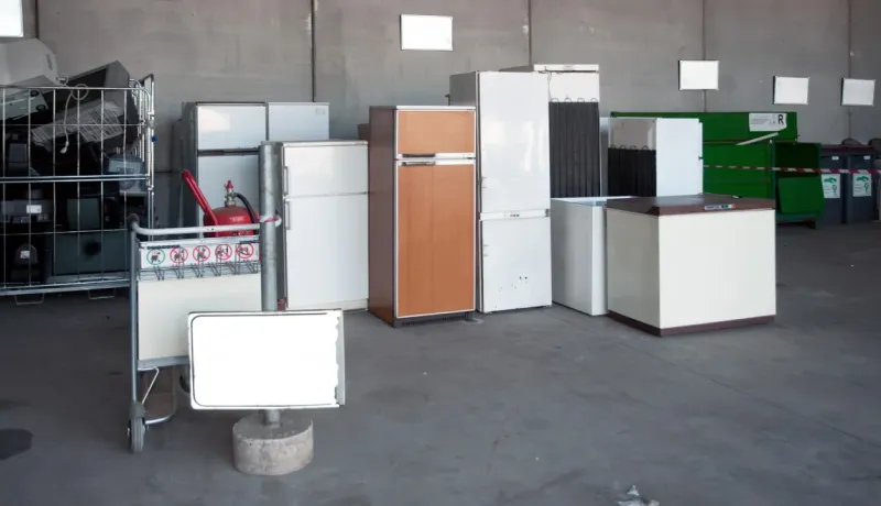 Appareils électroménagers usagés (réfrigérateurs) et déchets électroniques empilés dans un centre de recyclage.