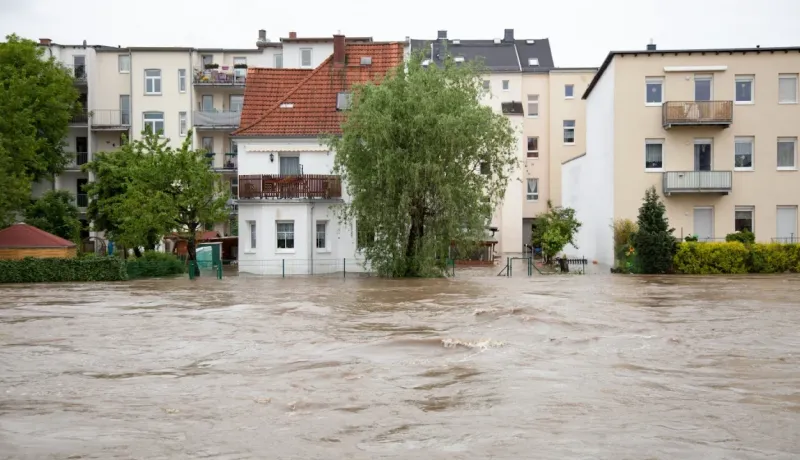Inondation. L'eau boueuse a envahi la rue devant des bâtiments résidentiels. Scène de catastrophe naturelle urbaine.