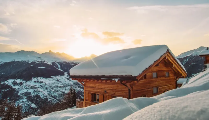 Un chalet en bois enneigé sous un ciel au coucher du soleil en montagne. Paysage d'hiver et de sports d'hiver.
