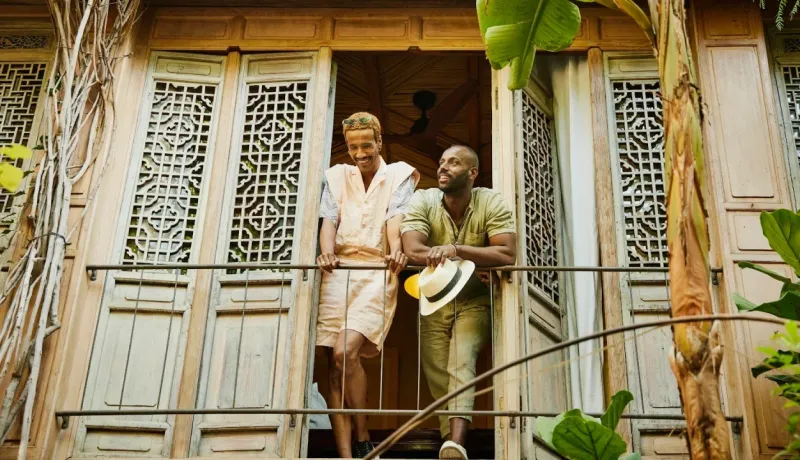 Deux hommes souriants et joyeux se tiennent sur le balcon en bois d'une maison exotique. Voyage et vacances.