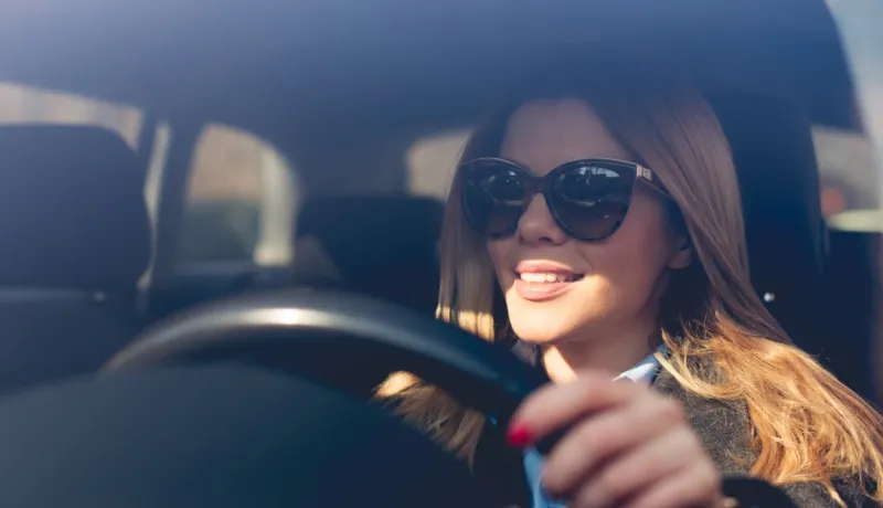 Une femme portant des lunettes de soleil conduit une voiture